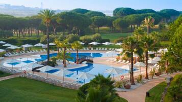 A resort with multiple swimming pools, sun loungers, and palm trees.