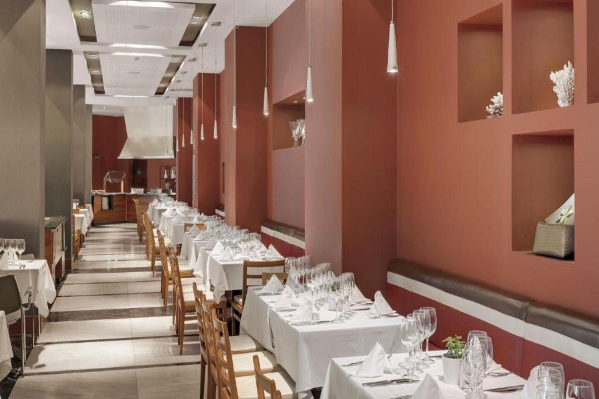 Een lange eetzaal met gedekte tafels, witte tafelkleden en hangende吊り足灯.