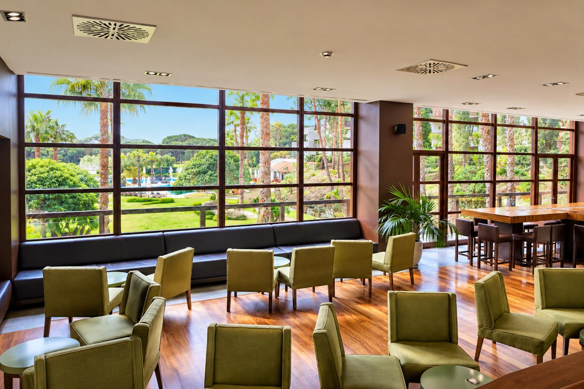 A spacious room with large windows offering a view of a landscaped garden.