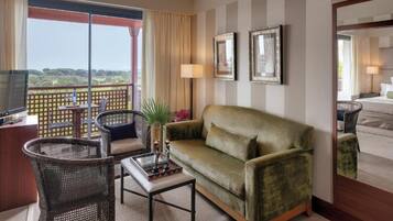 Habitación de hotel con balcón, sofá, mesa y televisión.