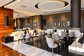 A modern lobby with a seating area, a reception desk, and a wall with framed artwork.