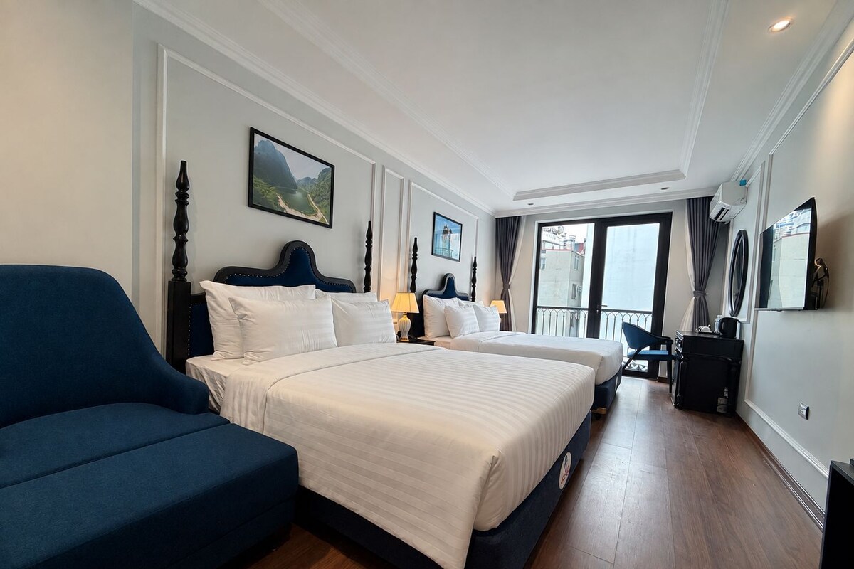 Quarto de hotel com uma cama grande, sofá, escrivaninha e varanda com vista.