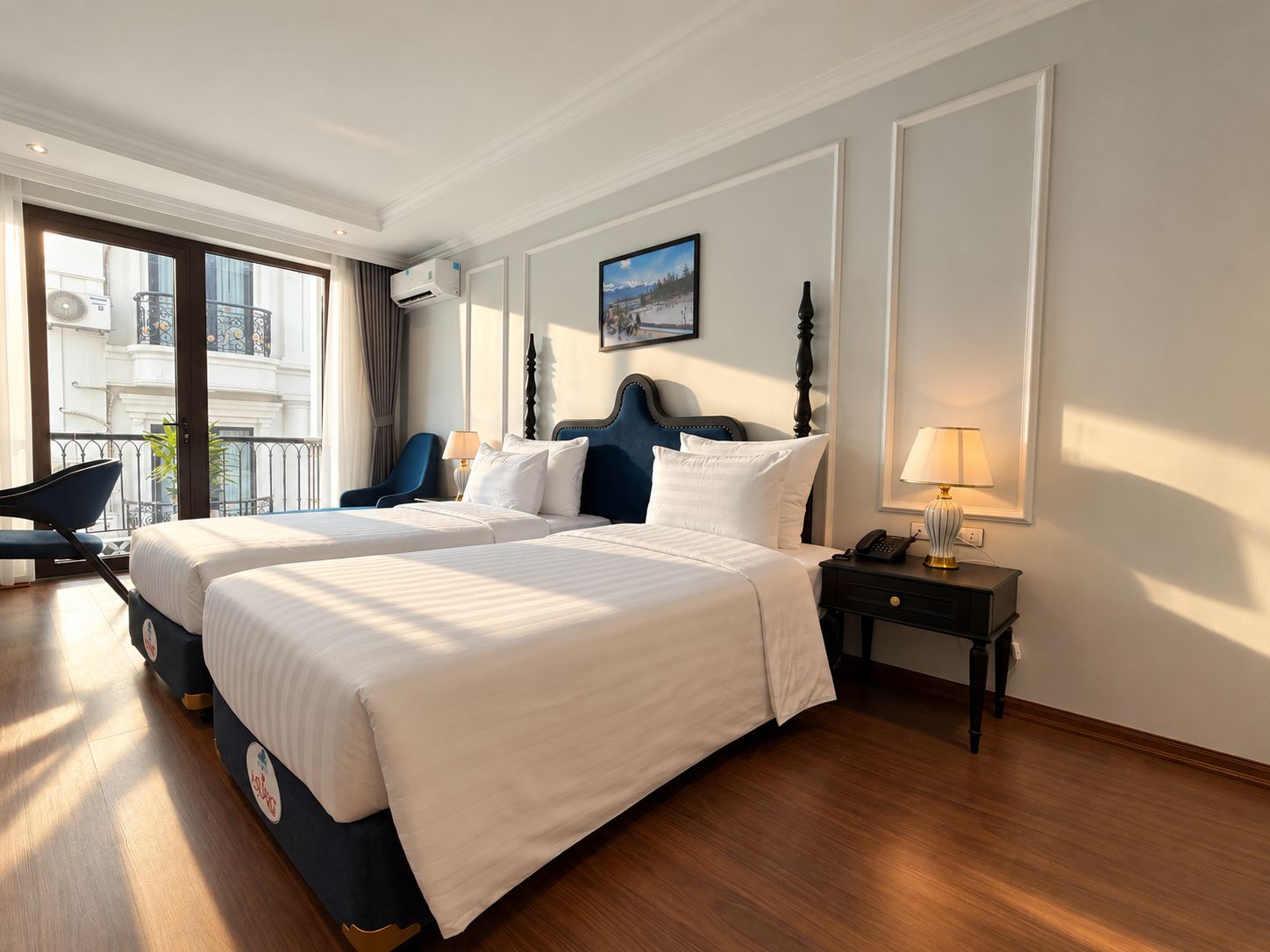 A hotel room with a large bed, a desk, a chair, a lamp, and a view of the outside.
