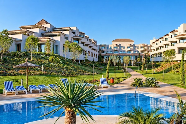 A resort with a swimming pool, lounge chairs, and a landscaped garden.