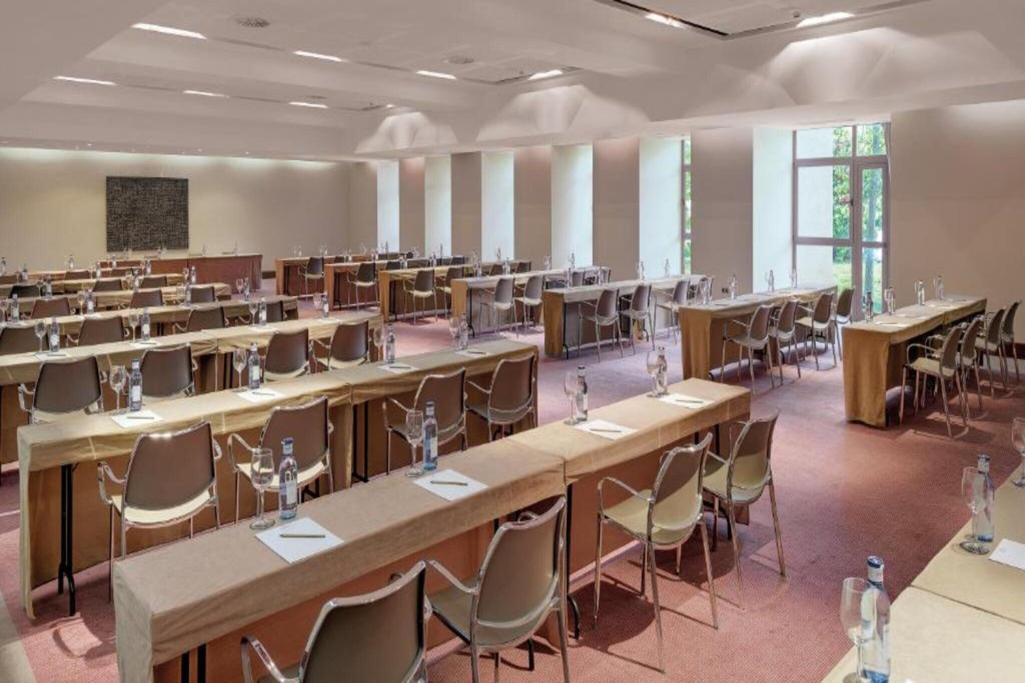 A conference room with multiple tables and chairs, equipped with water bottles and glasses.