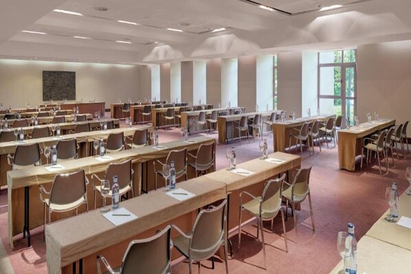 A conference room with multiple tables and chairs, equipped with water bottles and glasses.