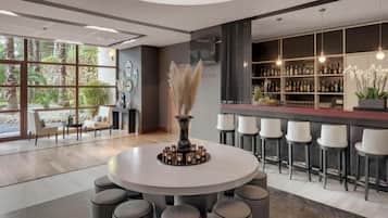 Een modern interieur met een ronde eettafel omringd door stoelen, een bar met krukken en een groot raam met uitzicht op groen.