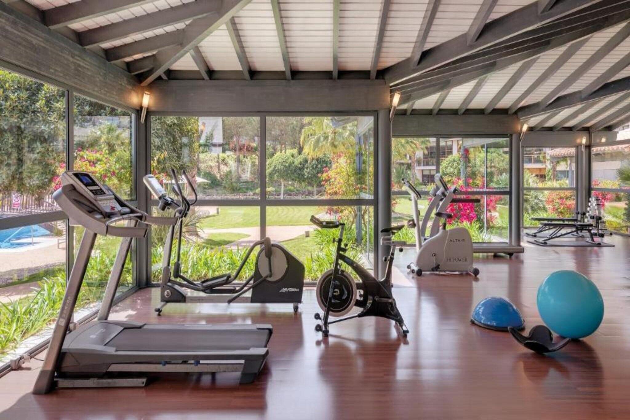 A gym with treadmills, stationary bikes, and exercise balls.
