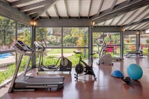 A gym with treadmills, stationary bikes, and exercise balls.