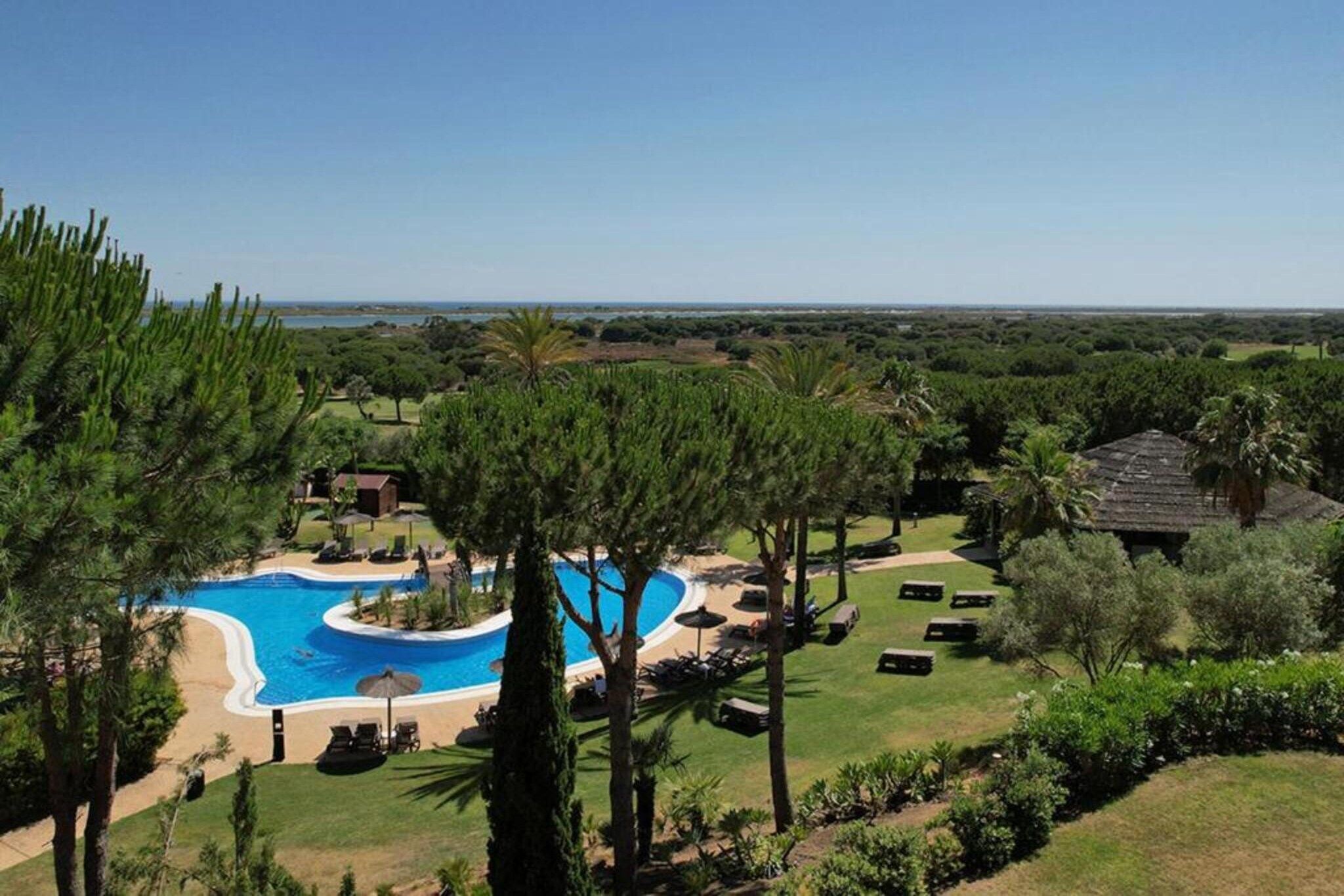 Un resort con una amplia piscina, sillas de descanso y vistas del paisaje circundante.