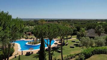Un resort con una amplia piscina, sillas de descanso y vistas del paisaje circundante.