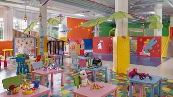 A colorful indoor play area with tables, chairs, and play structures.