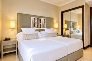 Een hotelkamer met een groot bed, nachtkastjes, een spiegel en wandlampen.