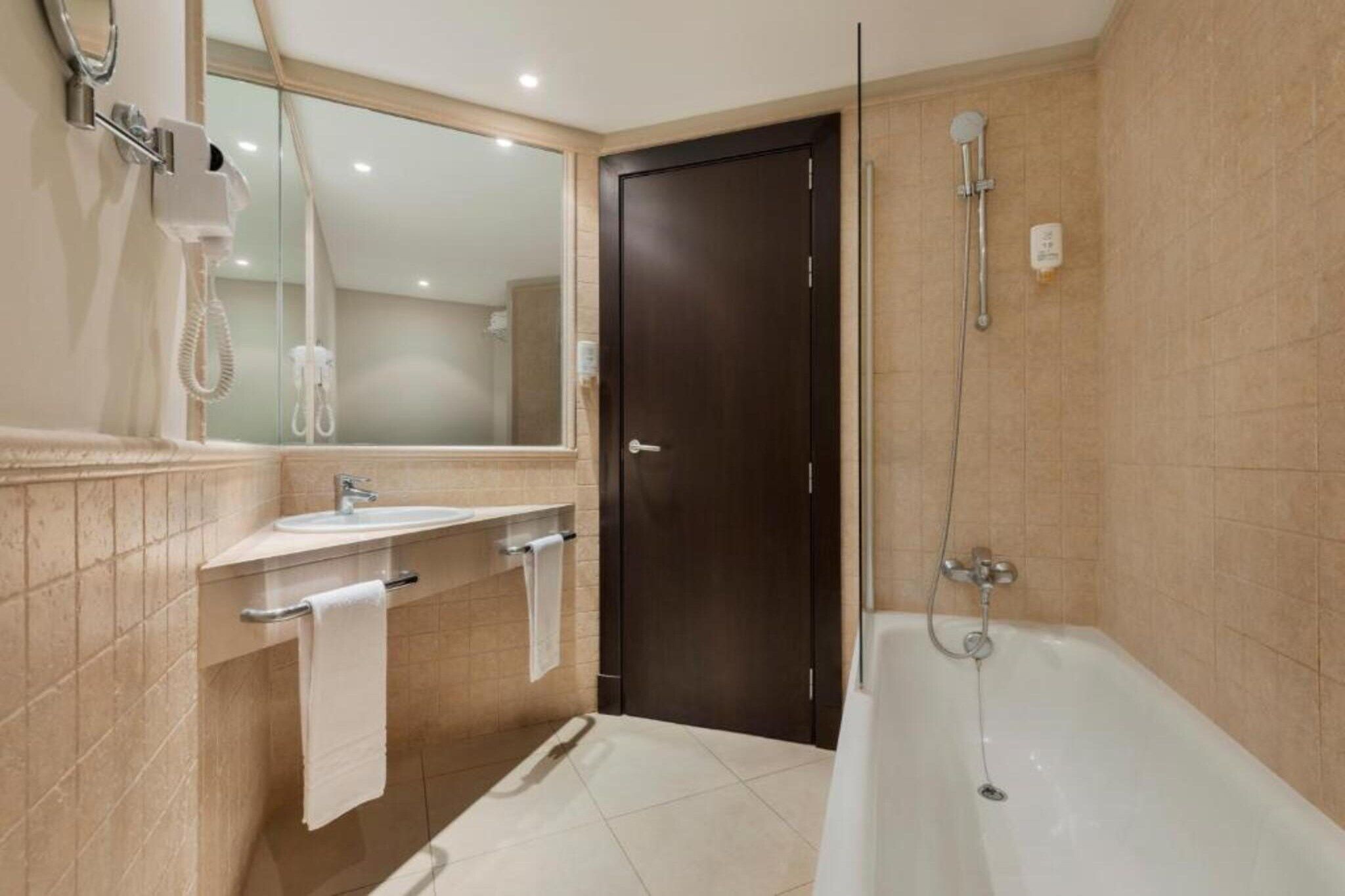 Un baño moderno con bañera, lavamanos y espejo.