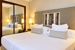 Een hotelkamer met een groot bed, een nachtkastje, een spiegel en een kunstwerk aan de muur.