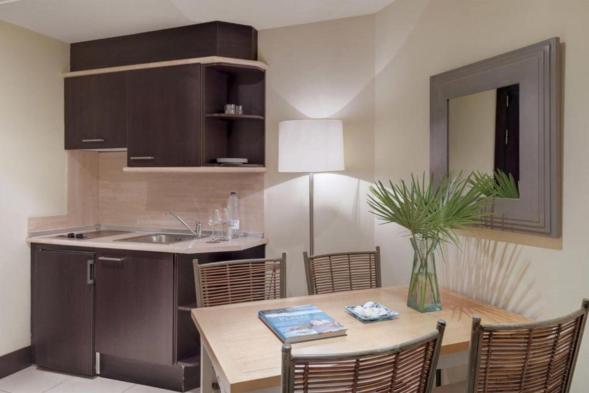 Cocina compacta con pileta, alacenas y comedor con sillas y una mesa.