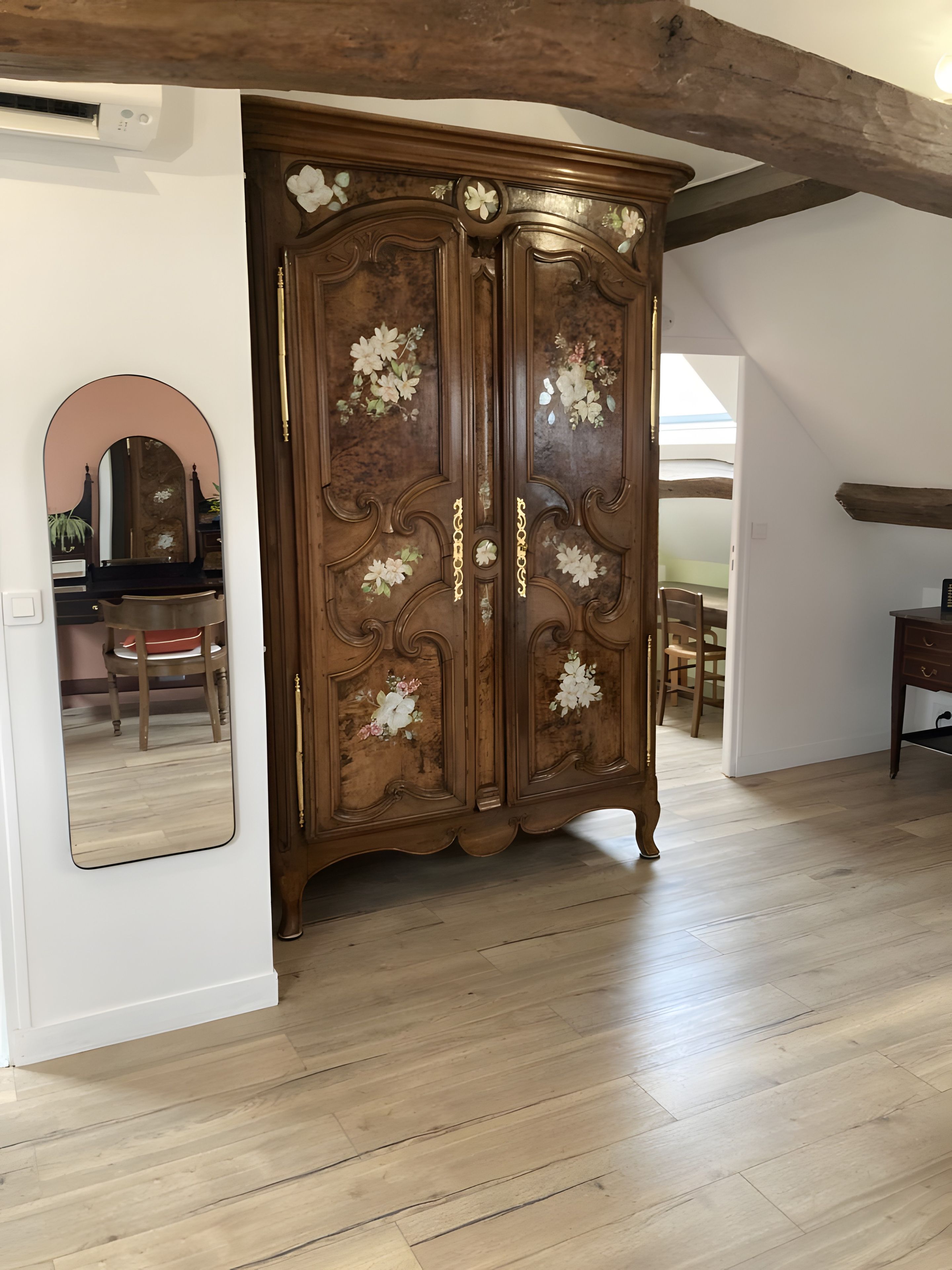 Een kamer met een grote houten garderobe, een spiegel en een piano.