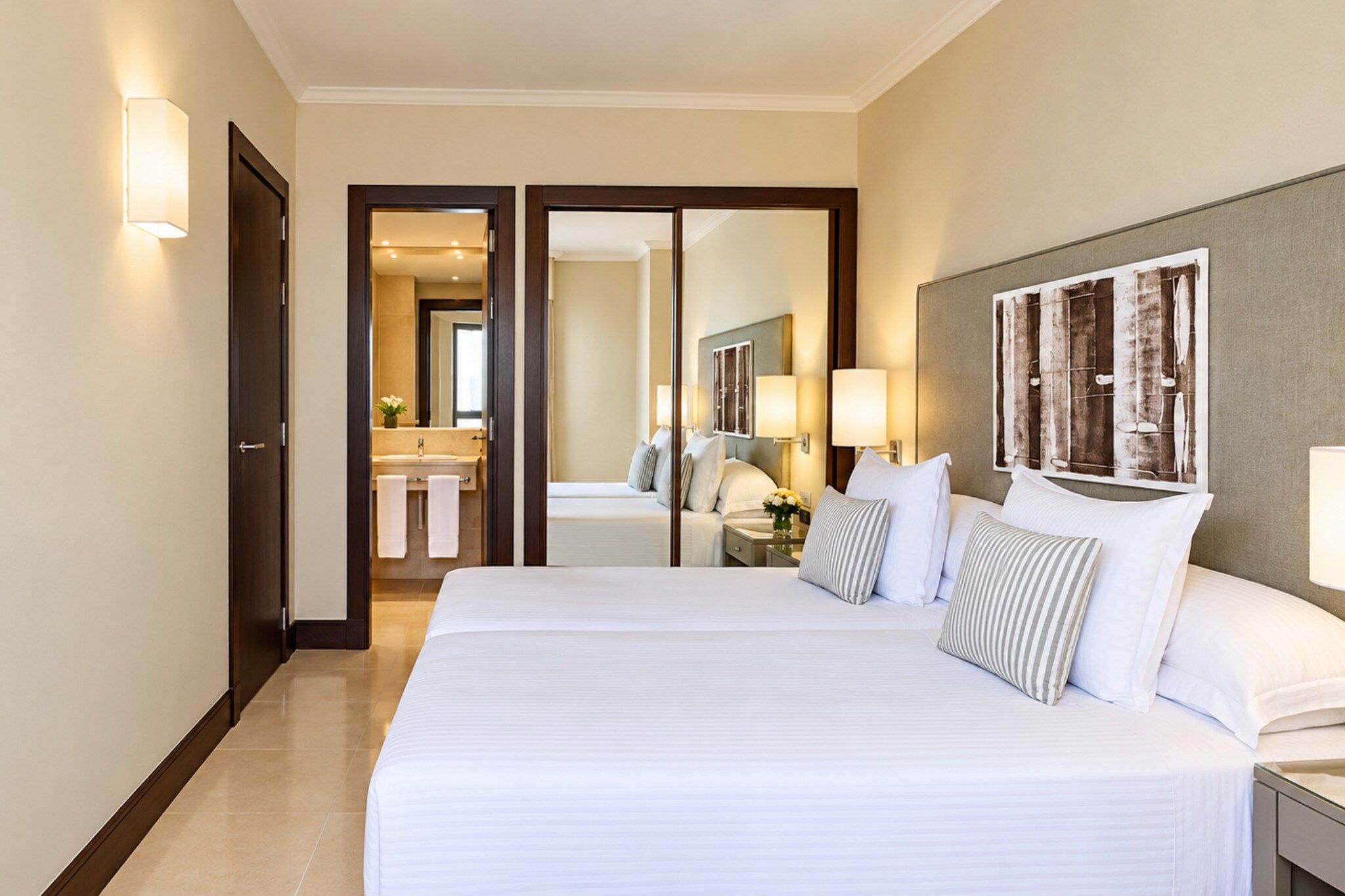 Una habitación de hotel con una cama grande, un baño con espejo y vistas al pasillo.