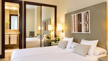 A hotel room with a large bed, a bathroom with a mirror, and a painting on the wall.