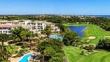 A golf course with a swimming pool and a building with multiple balconies.