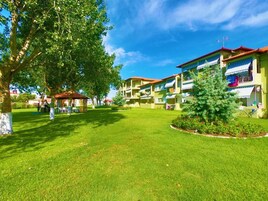 A courtyard with a lawn, trees, and a building with balconies.