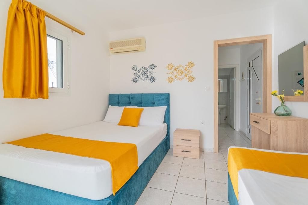 Een slaapkamer met een bed, nachtkastje, spiegel en een deur naar een badkamer.