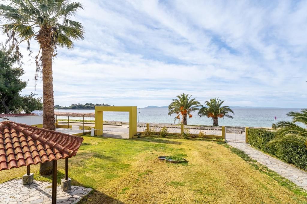 Une propriété située sur la côte, dotée d’une terrasse dallée, de palmiers et offrant une vue sur la mer.