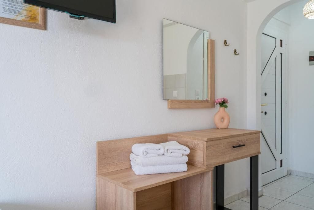 Een badkamer met een houten wastafelmeubel, een spiegel en een stap handdoeken.