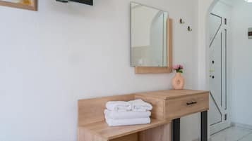 Een badkamer met een houten wastafelmeubel, een spiegel en een stap handdoeken.