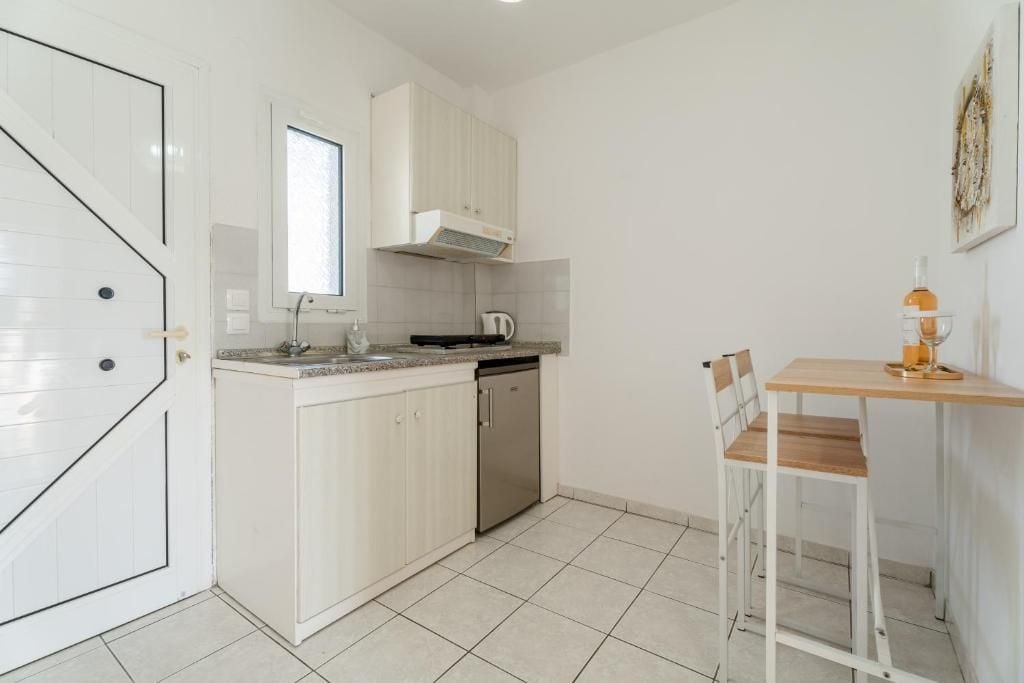 A compact kitchen with white cabinetry, a dishwasher, and a small dining area with a table and chair.