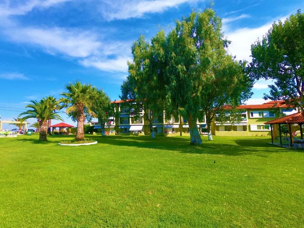 A hotel courtyard with a well-maintained lawn, several trees, and a building with a red roof in the background.