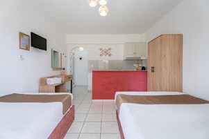 Habitación de hotel con dos camas, kitchenette, televisión y baño.
