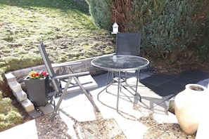An outdoor patio with a round table and chairs, a potted plant, and a large vase. - Holiday apartment with 2 bedrooms (Simmerath)