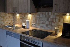 Ett modernt kök med inbyggd diskmaskin, spishäll och kaffebryggare.