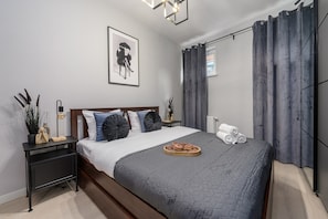 A modern bedroom with a bed, a bedside table, a nightstand, a framed picture, and a window with curtains. - Lumina 2BR Apt w/ Parking & Balcony & AC (Warszawa)