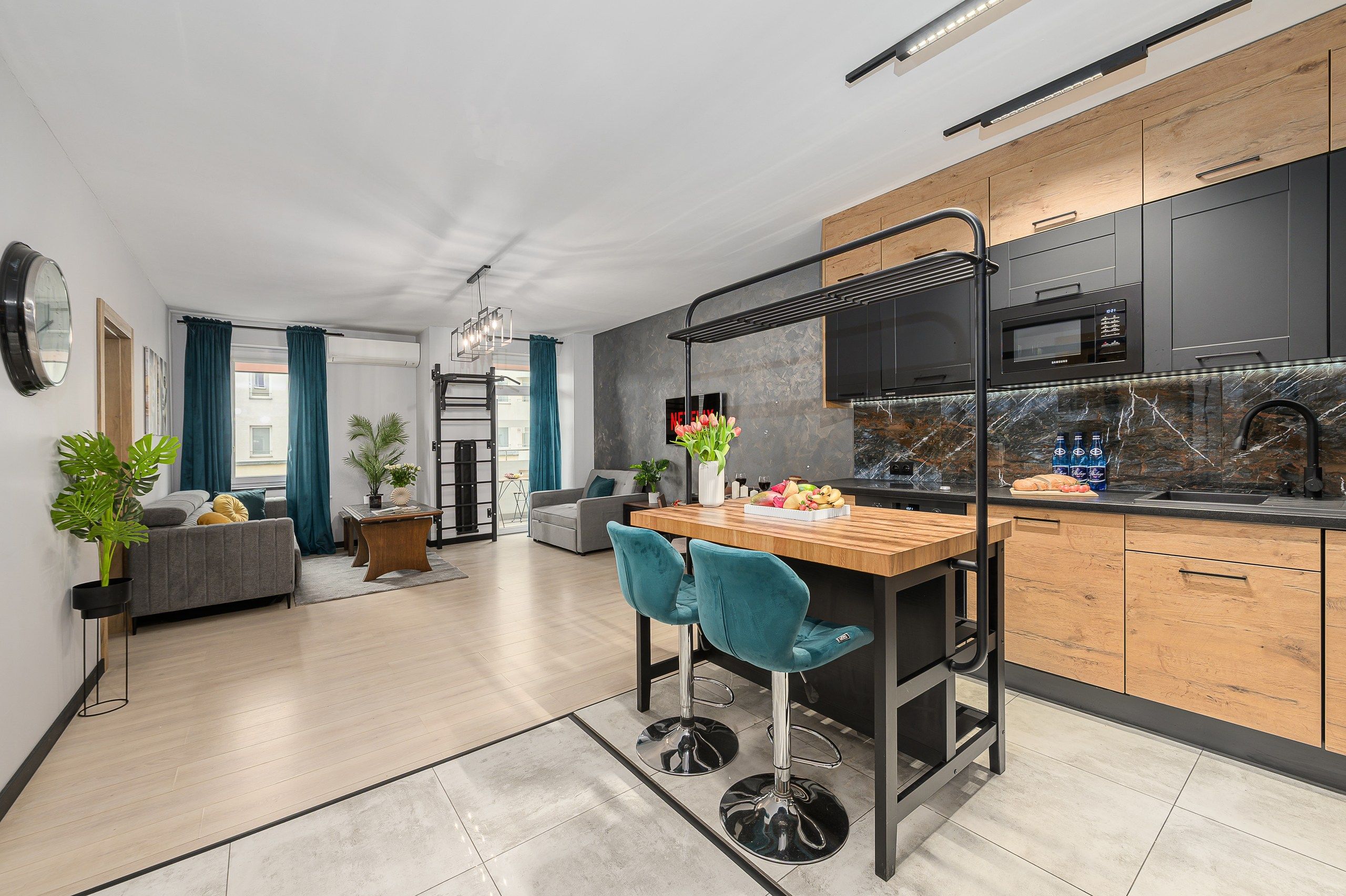 Una cucina moderna con isola centrale, sgabelli da bar e zona pranzo con divano e tavolino.