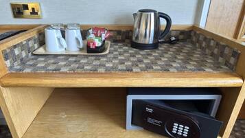 Una kitchenette con cafetera, teteras y un hervidor sobre una encimera a cuadros.