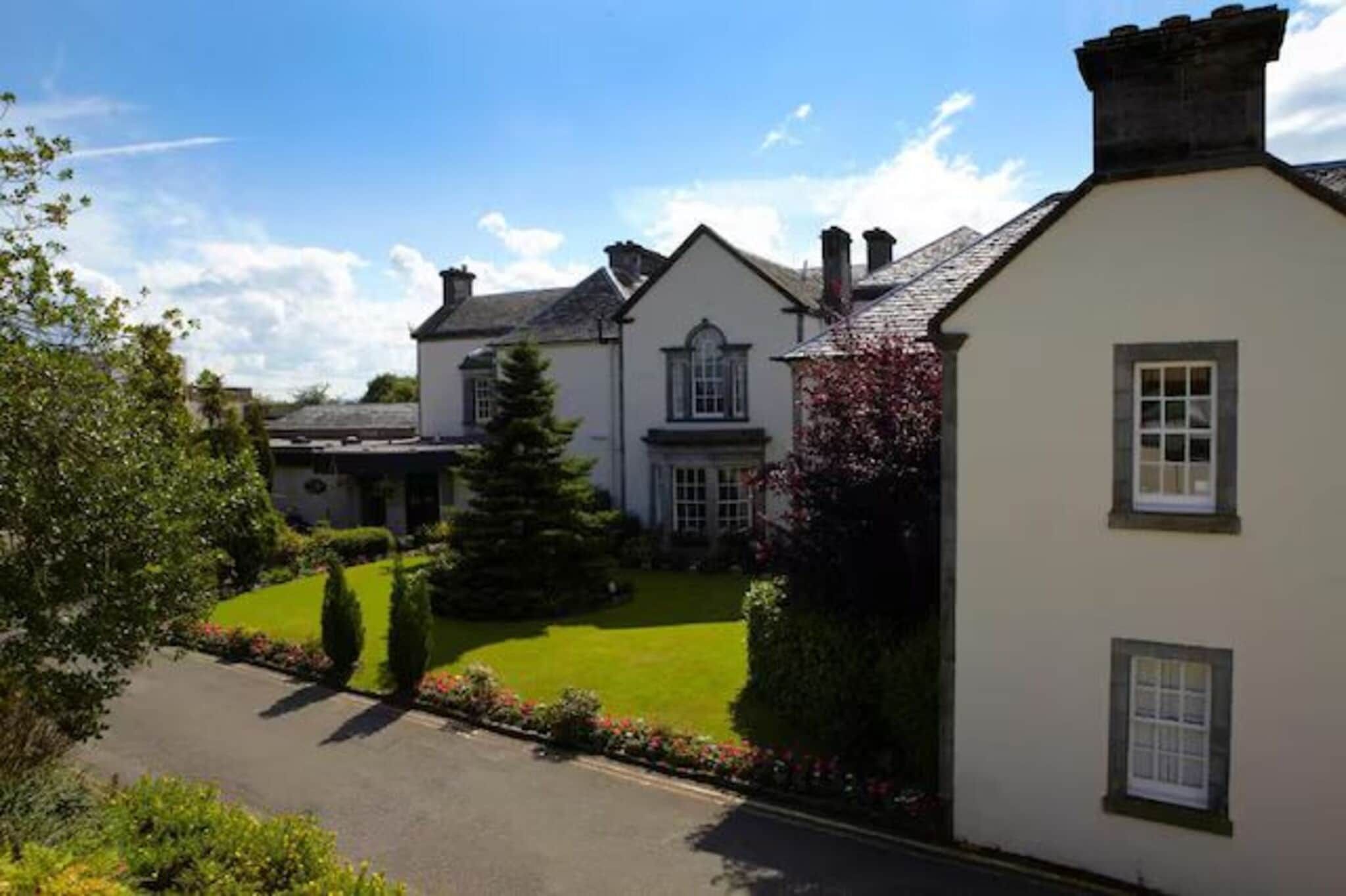 A two-story house with a well-maintained lawn and a driveway.