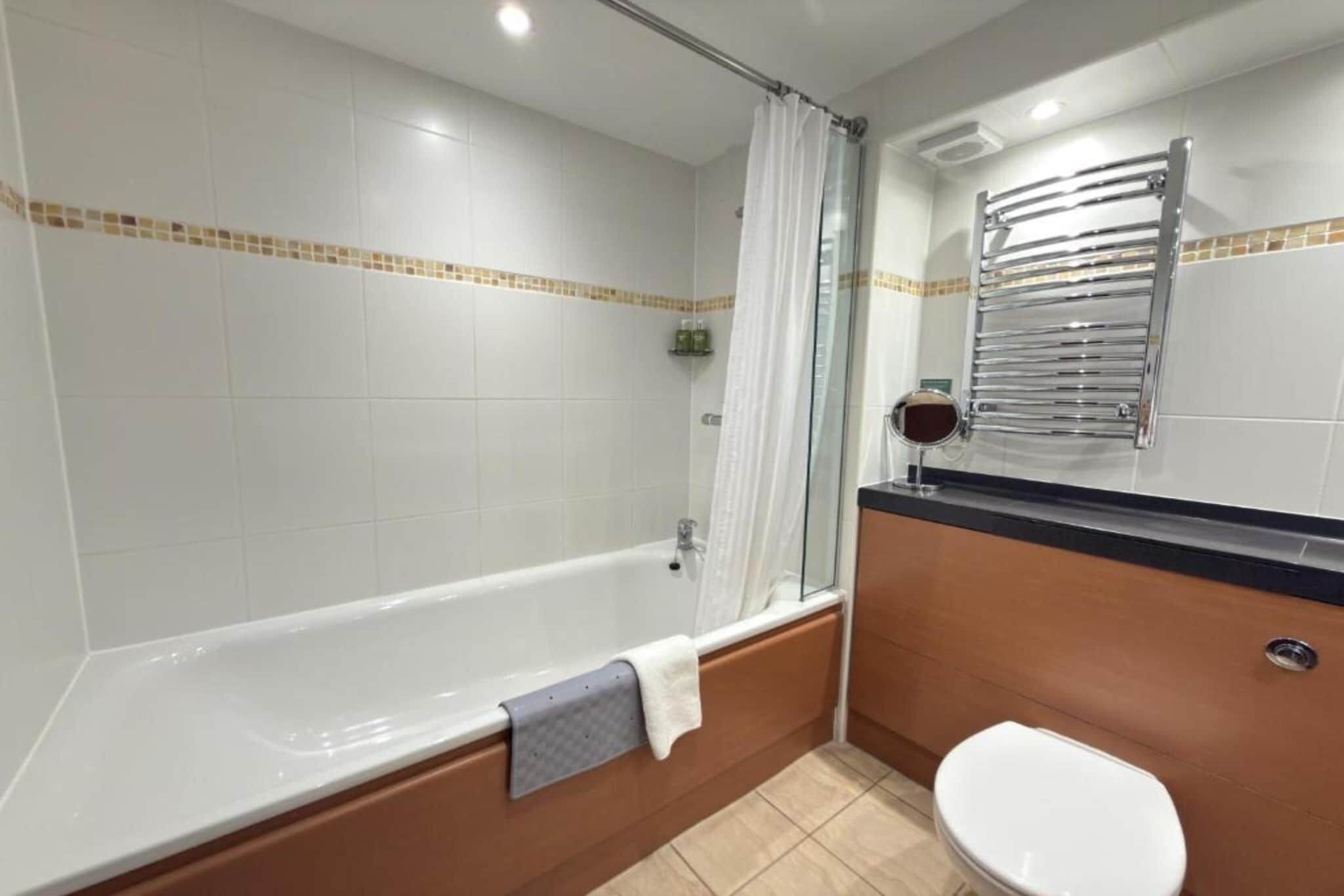 Ein Badezimmer mit Badewanne, Toilette und Duschbereich.