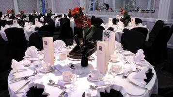 A formal dining setup with round tables, numbered place settings, and floral centerpieces.