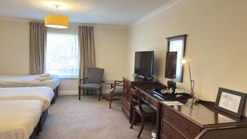 A hotel room with two beds, a desk with a chair, a television, and a window with curtains.