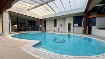 Ein Hallenbad mit Glasdecke, gefliestem Boden und einem Schild mit der Aufschrift 'Nicht springen'.
