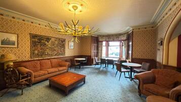 Ein Zimmer mit Teppichmuster, einer Couch, einem Couchtisch, einer Kandelaber und einem Gemälde an der Wand.