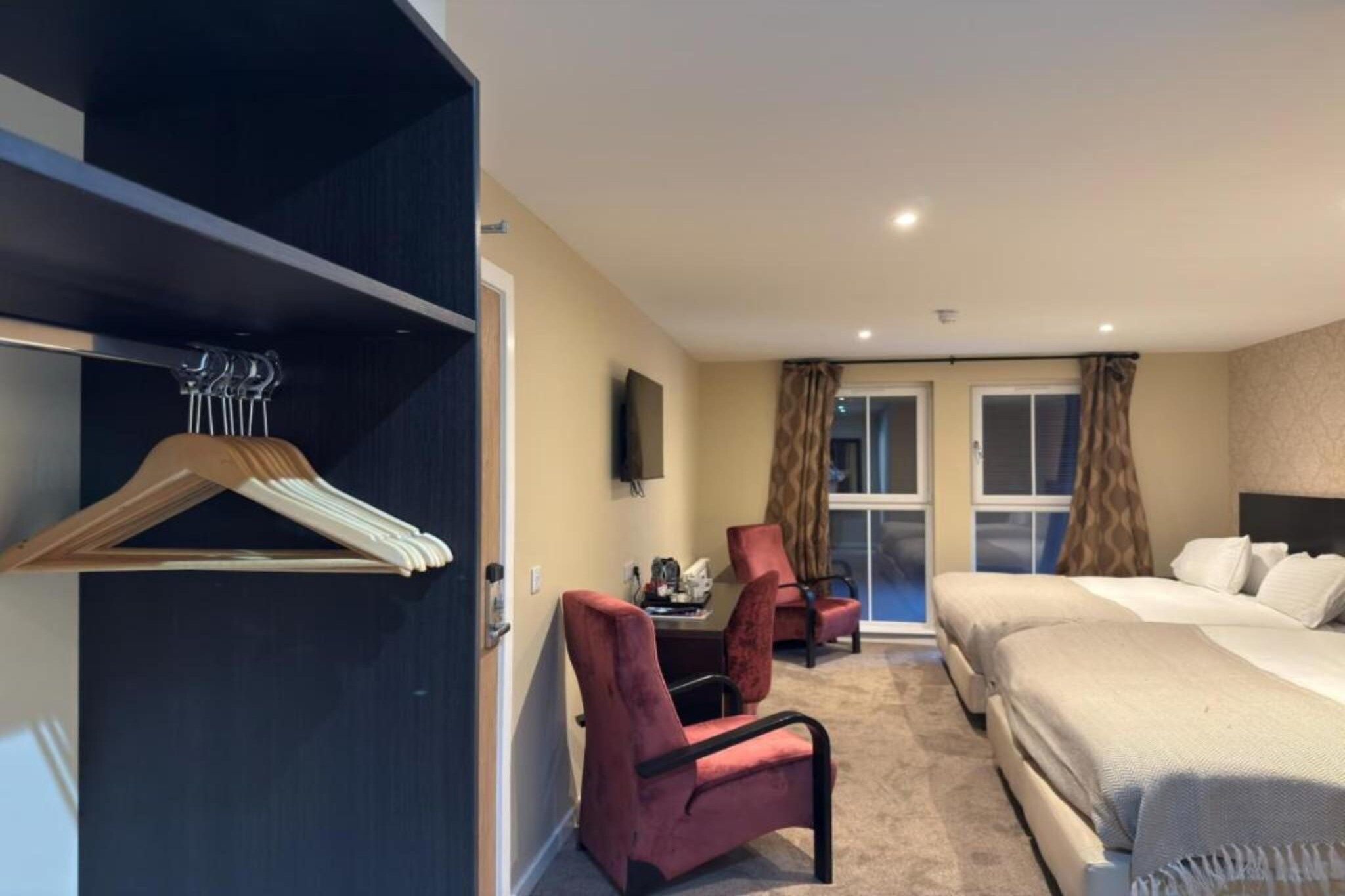 A hotel room with a bed, a desk, a chair, a wardrobe, and a television.