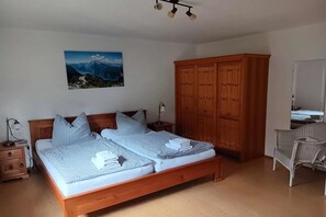 Un lit double avec une couette à carreaux, une armoire en bois, une chaise et un tableau accroché au mur.