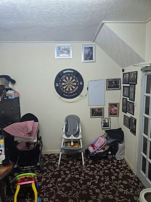 Quarto com dardos, carrinho de bebê, andador e porta com janela.
