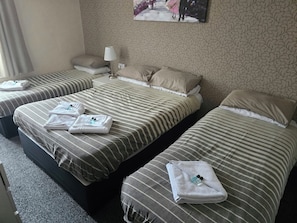 A hotel room with three beds, each with striped bedding and towels. - charnley gold hotel (Blackpool)