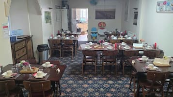 A dining area with multiple tables and chairs, a patterned carpet, and a ceiling fan.