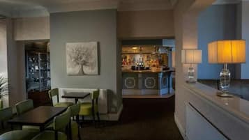 A hotel room with a dining area, a bar, and a view of the city.