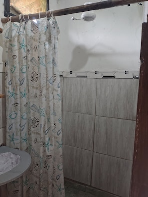 A bathroom with a shower curtain featuring sea creatures, a toilet, and a tiled wall.
